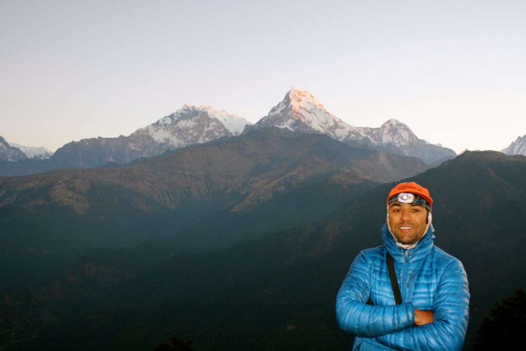 Trekker from 12 Days Annapurna Circuit Trek standing at a scenic viewpoint with the snow-capped mountain range in the Himalayas of Nepal.