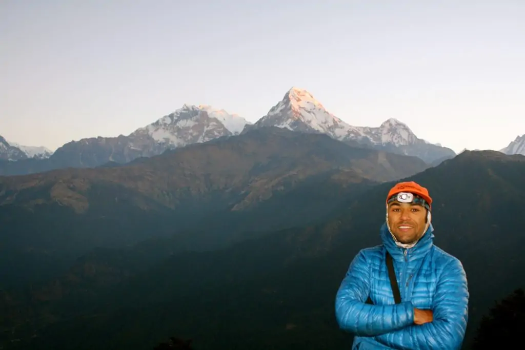 Trekker from 12 Days Annapurna Circuit Trek standing at a scenic viewpoint with the snow-capped mountain range in the Himalayas of Nepal.