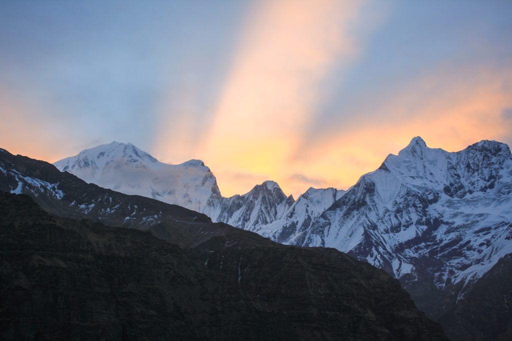 A ray of sunlight piercing through the clouds, illuminating part of the mountain range in Nepal.