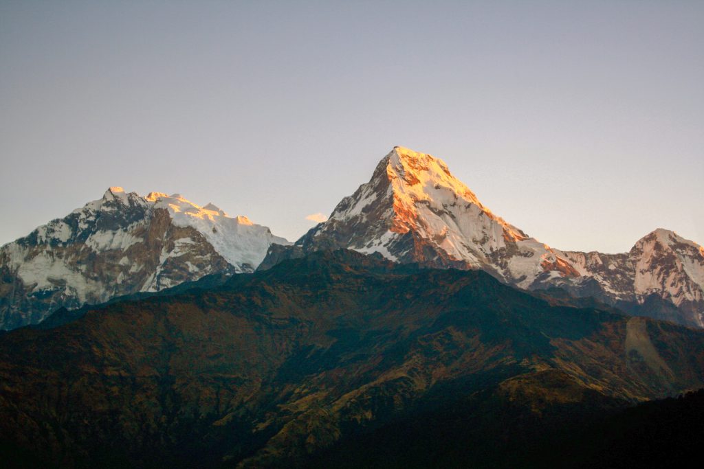 Golden sunrise over the snow-covered Annapurna mountain range seen from Annapurna Base Camp Trek.