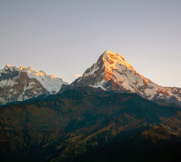 Golden sunrise over the snow-covered Annapurna mountain range seen from Annapurna Base Camp Trek.