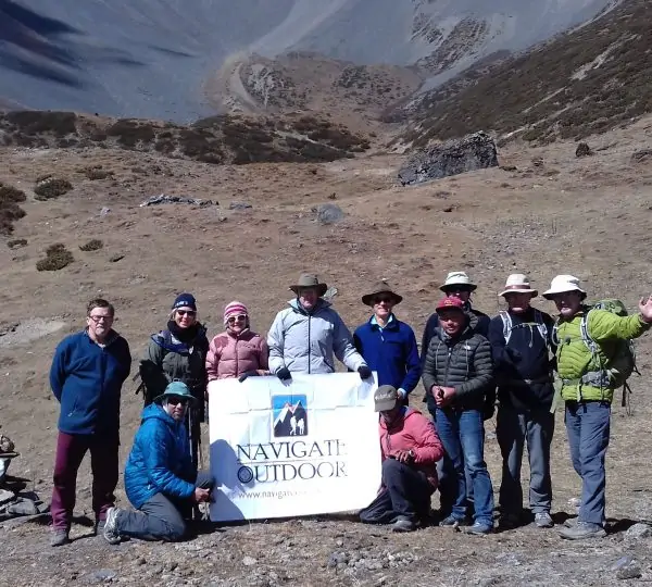 A group of trekkers being guided by Navigate Outdoor staff at an outdoor Himalayan site, surrounded by mountains and natural scenery.