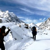 A group of trekkers walking along a rugged mountain trail surrounded by towering peaks on the way to Kanchenjunga Base Camp Trekking.
