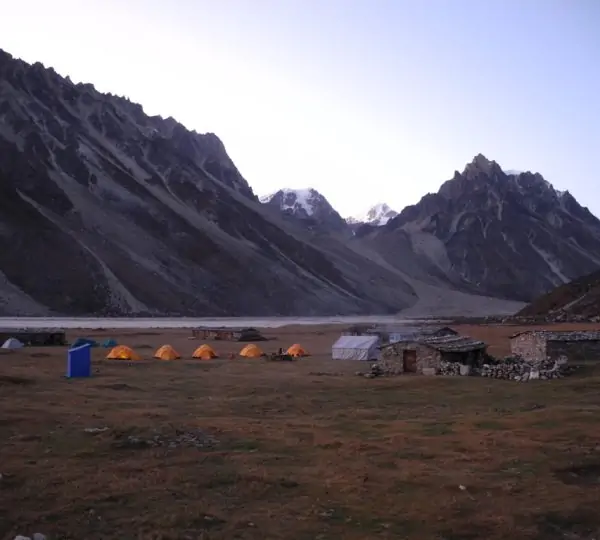 Tents set up at Base Camp with towering snow-capped mountains rising in the background in Nepal.