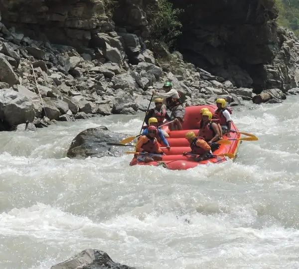 Group of rafters paddling through whitewater rapids on the Tamor River, surrounded by lush forested hills in eastern Nepal.