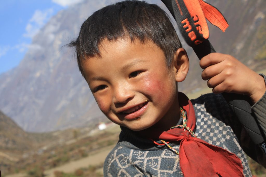 Portrait of a cheerful local boy smiling warmly around Tsum Valley Trekking