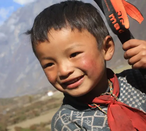 Portrait of a cheerful local boy smiling warmly around Tsum Valley Trekking; himalayan adventures.