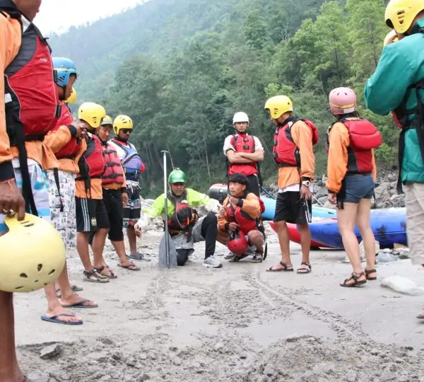 A group of outdoor enthusiasts attentively listening to their guide during a briefing session before starting their rafting.