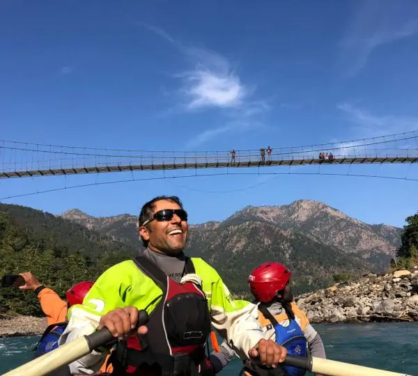 Group of people happily rafting through rapids on the Karnali River