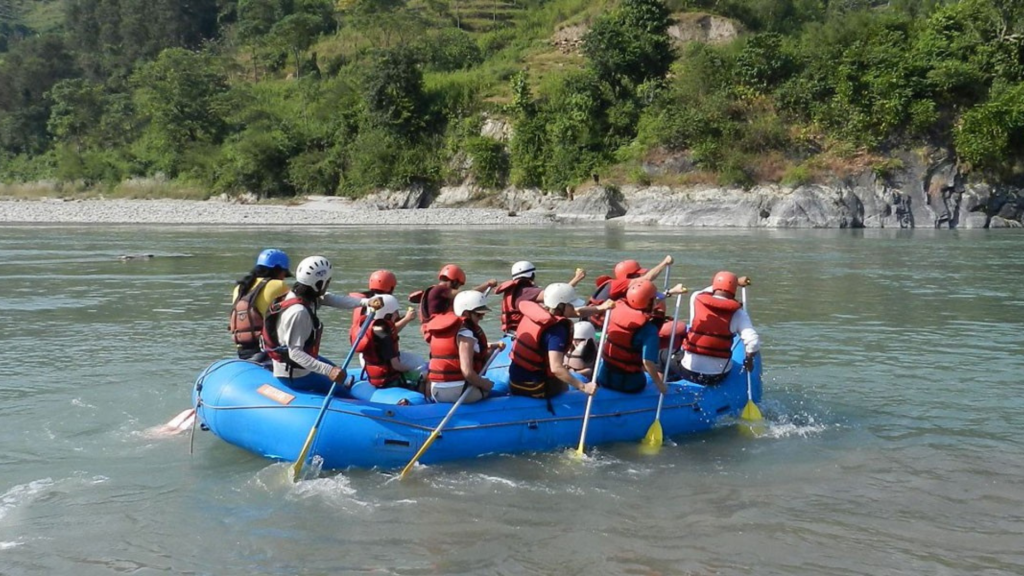 Rafting group navigating the rapids of the Sunkoshi River surrounded by lush green hills in Nepal.
