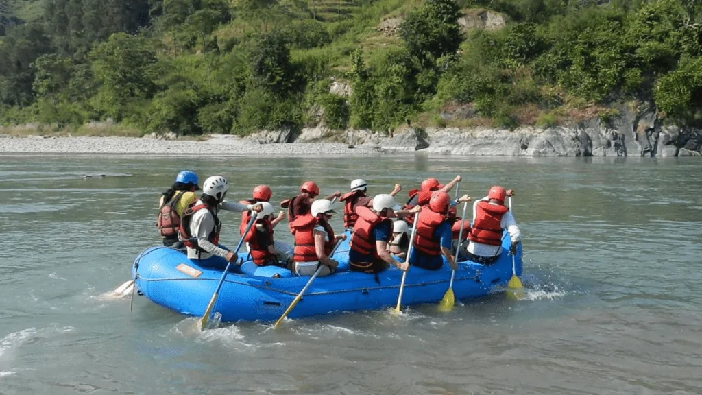 Rafting group navigating the rapids of the Sunkoshi River surrounded by lush green hills in Nepal.