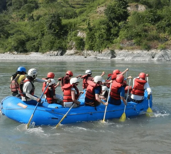 Rafting group navigating the rapids of the Sunkoshi River surrounded by lush green hills in Nepal.
