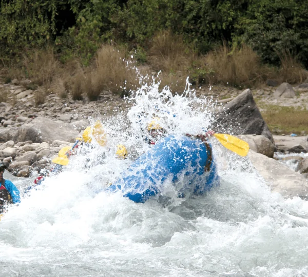 Rafting, navigating the thrilling rapids of the Sunkoshi River, surrounded by lush green hills and forests in Nepal.