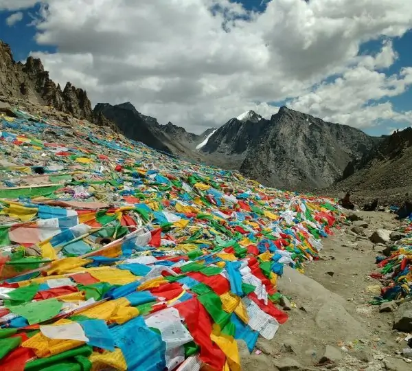 Vibrant prayer flags fluttering along a mountain trail in the Himalayas, symbolizing peace and blessings for trekkers.