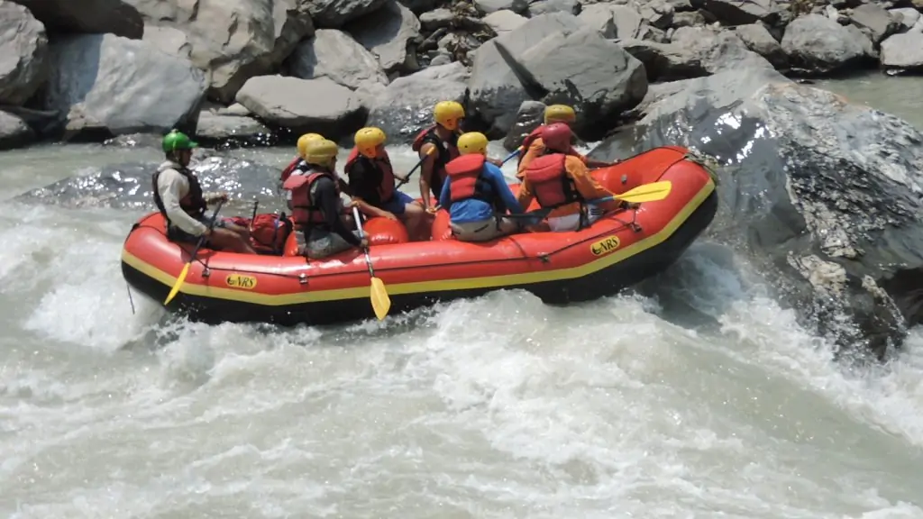 A group of rafters paddling together in a raft navigating whitewater rapids surrounded by lush greenery.