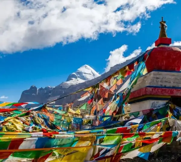Vibrant prayer flags fluttering in the wind around Mount Kailash, set against the backdrop of the sacred Himalayan landscape.